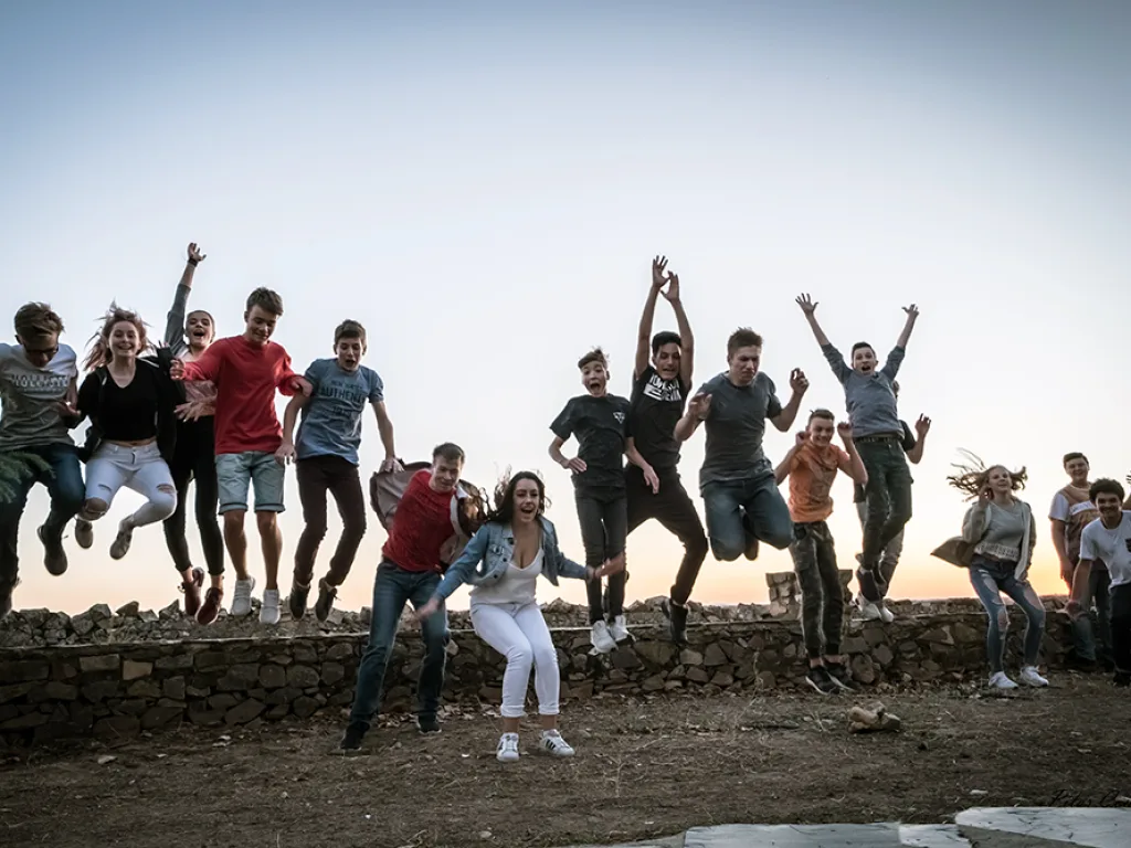 Eine Gruppe springt gemeinsam vor dem Abendhimmel in die Luft.
